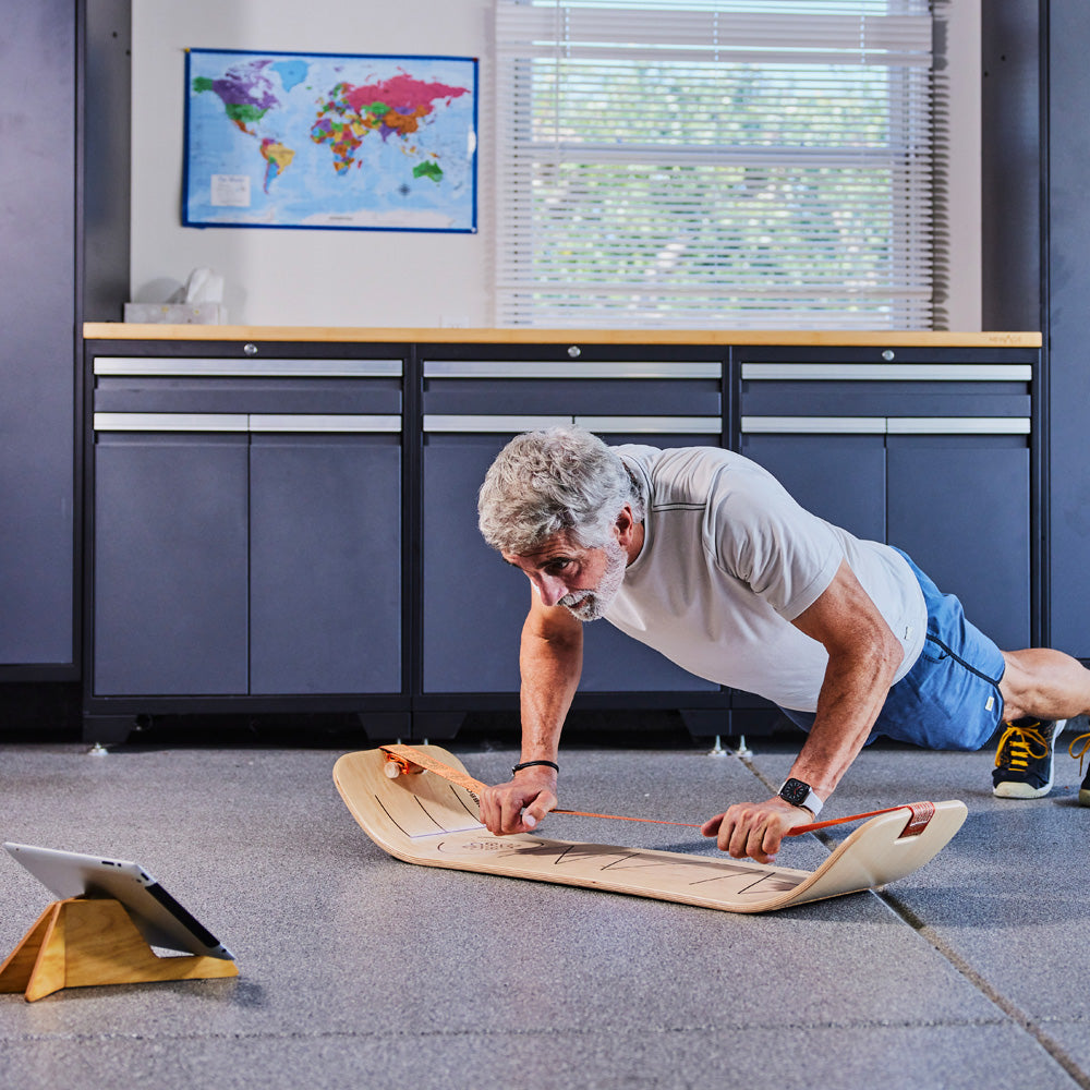 Mid-aged man using Gibbon SlackBoard as a core training balance board performing pushup with hands positioned on the slack line webbing