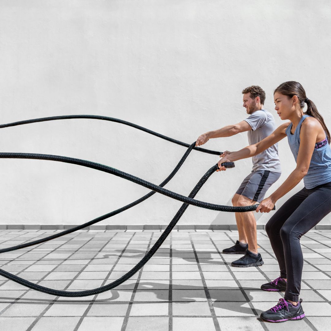 Two people using battle ropes outdoors on a sunny day. Fitter1 Canada supplies Canadian fitness equipment