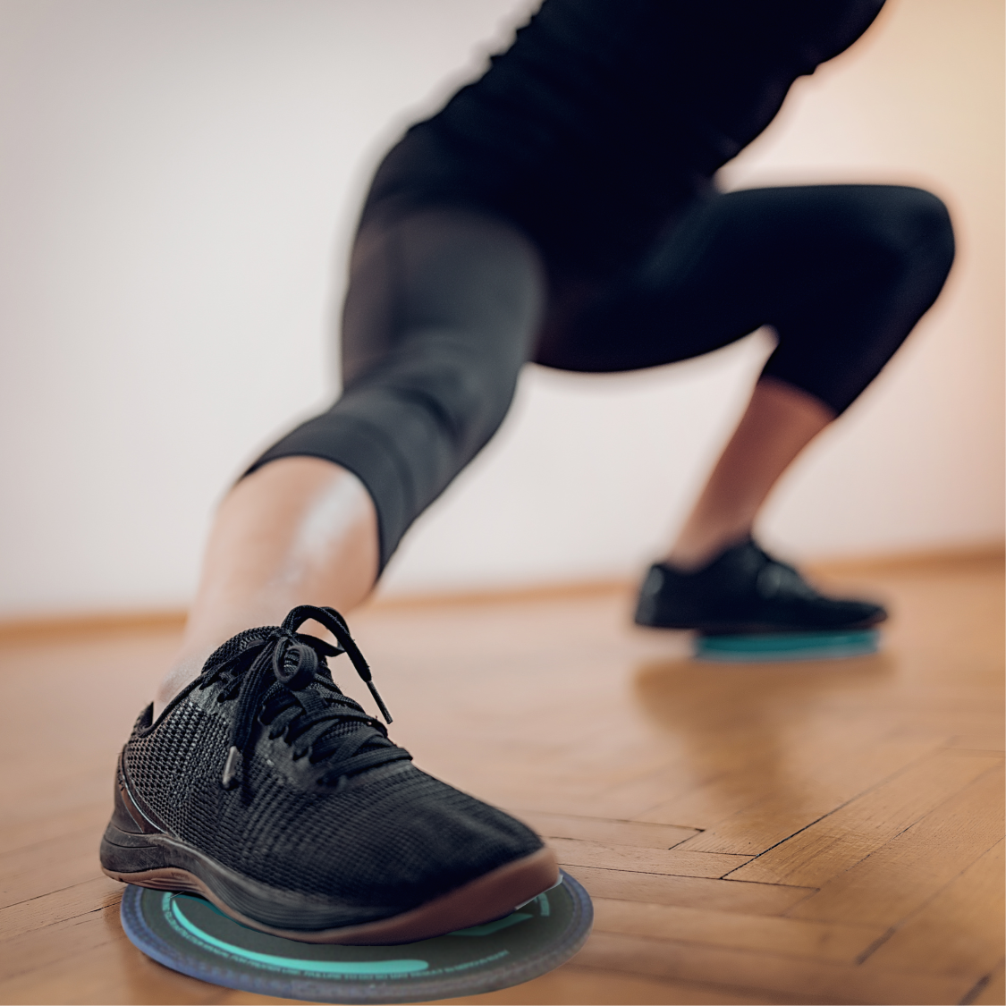 Woman doing deep side lunge with gliding discs under feet for lower body strength and flexibility training